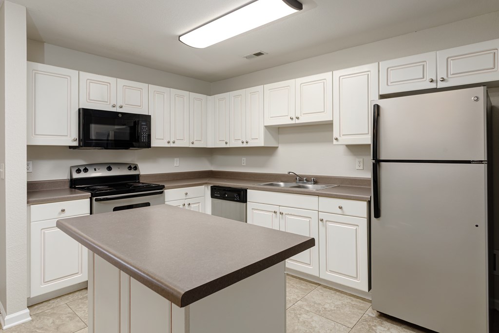 A kitchen with white cabinets and a black countertop.