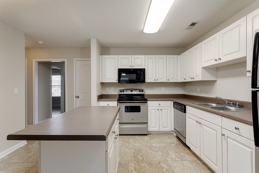 A kitchen with white cabinets and a black refrigerator.