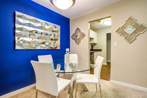 A dining room with a glass table and white chairs.