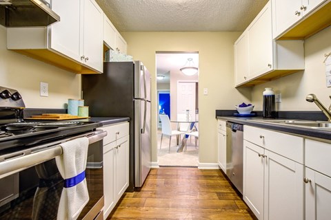 A kitchen with a black refrigerator and white cabinets.