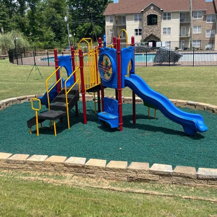 a childrens playground with slides and chairs in a park