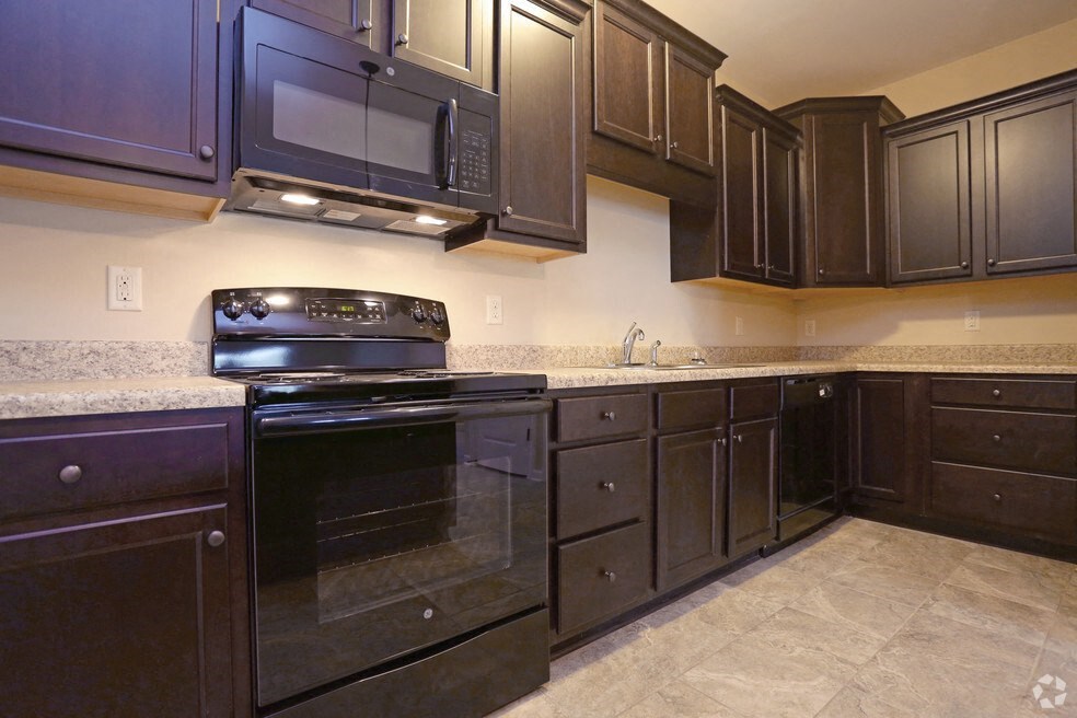 a kitchen with dark wood cabinets and black appliances