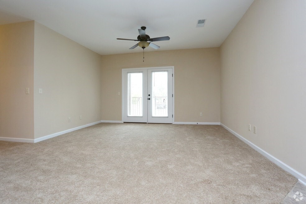 an empty living room with a ceiling fan