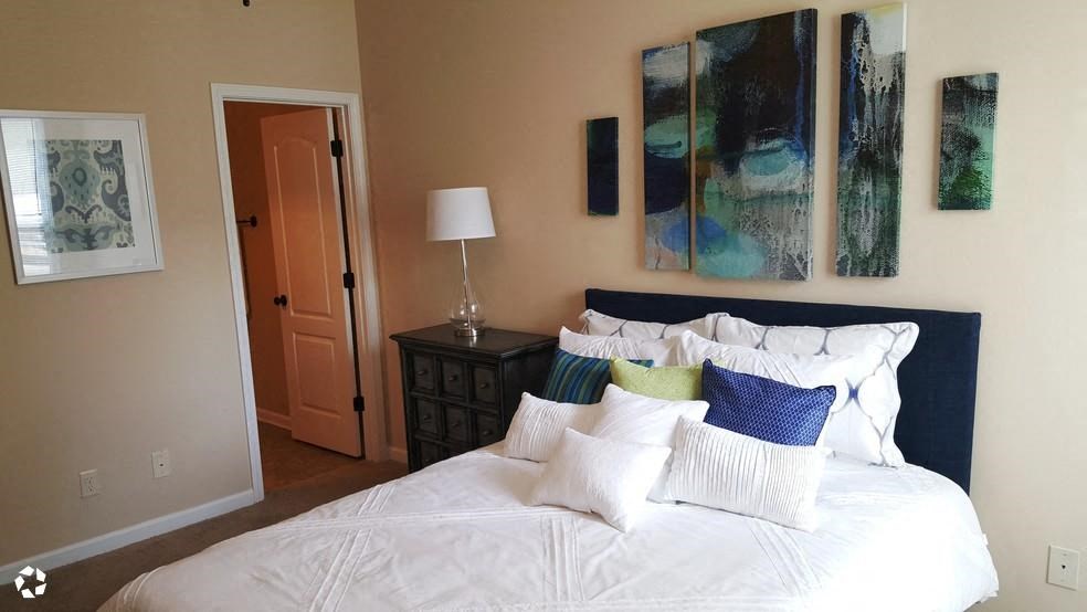 a bedroom with a white bed and paintings on the wall