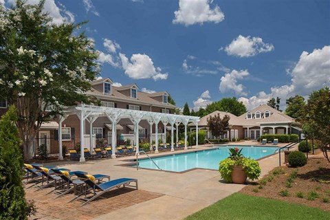 A pool area with sun loungers and a building in the background.