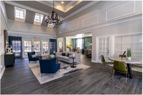A spacious living room with a dark blue sofa and a chandelier.