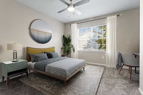 A bedroom with a bed, a side table, a chair, and a plant.