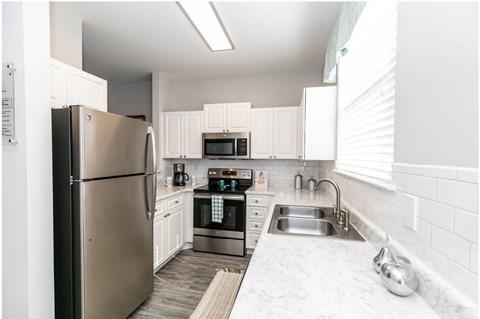 A modern kitchen with stainless steel appliances and white cabinets.