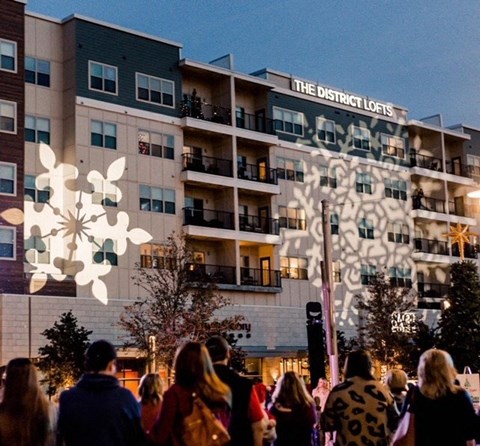 a crowd of people walking in front of an apartment building with a projected snowflake