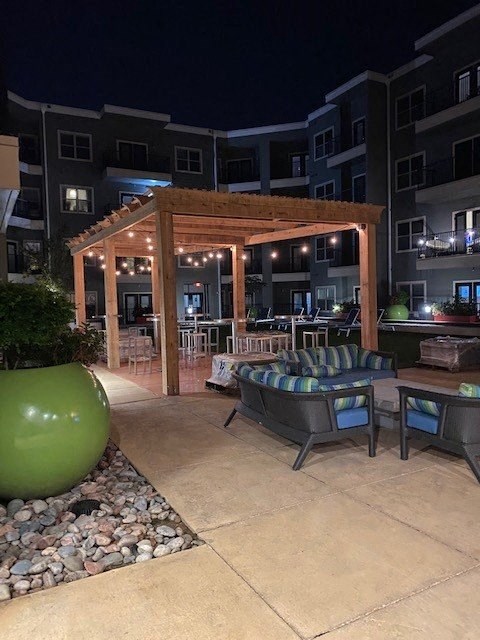 a patio with a couch and chairs in front of an apartment building