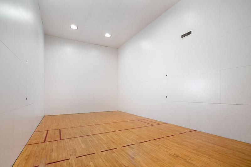 a large white room with a wooden racquetball court