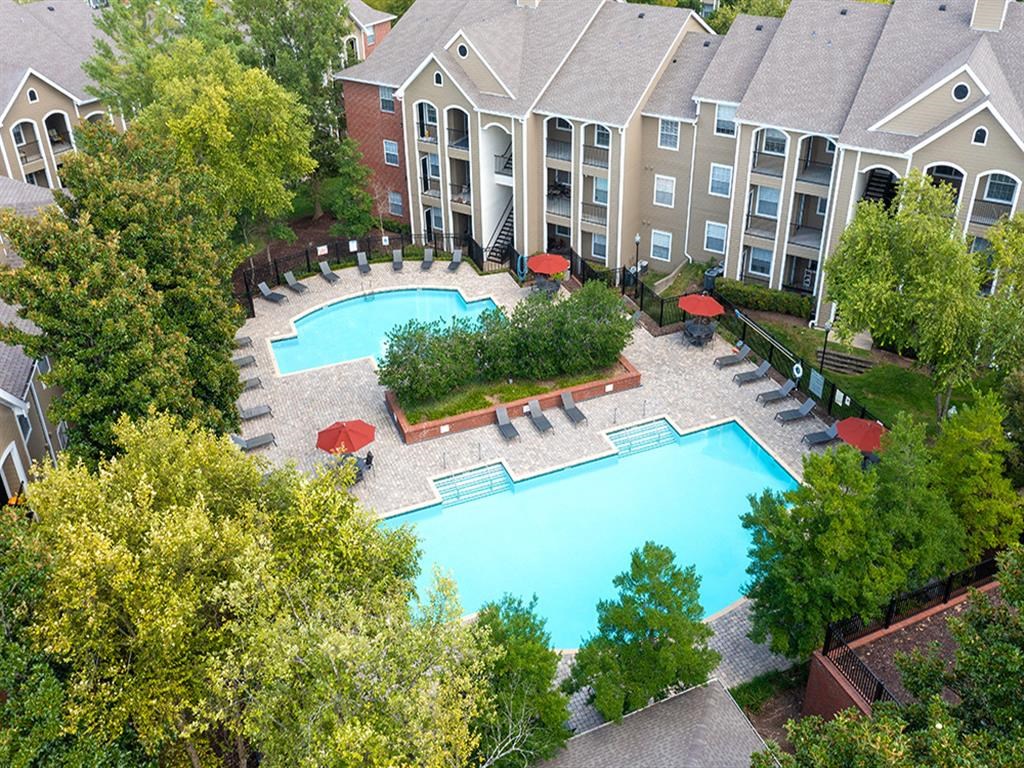 an aerial view of a large swimming pool in front of an apartment building