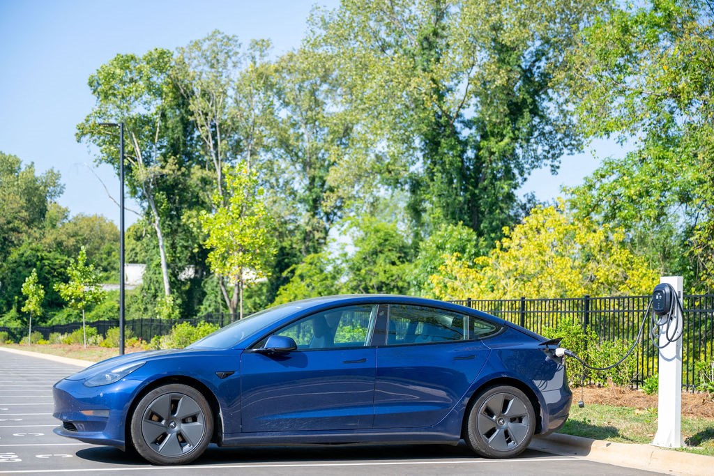 the electric car is parked next to a parking meter