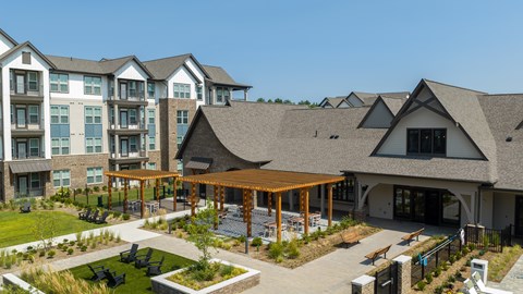 A large building with a covered walkway and a grassy area in front.