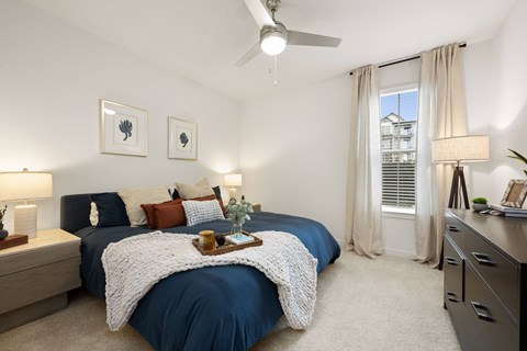 A bedroom with a blue bedspread and a white blanket on the bed.