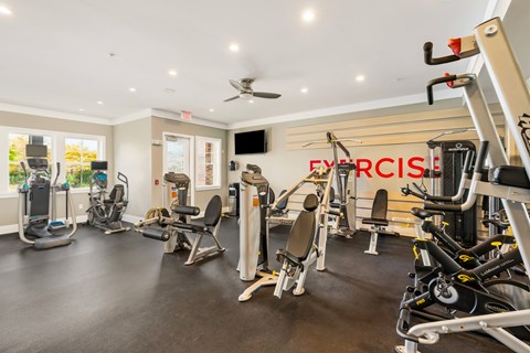 A gym with a variety of exercise equipment including treadmills, stationary bikes, and weight machines.