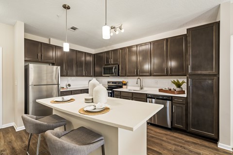 A kitchen with a white island and dark brown cabinets.