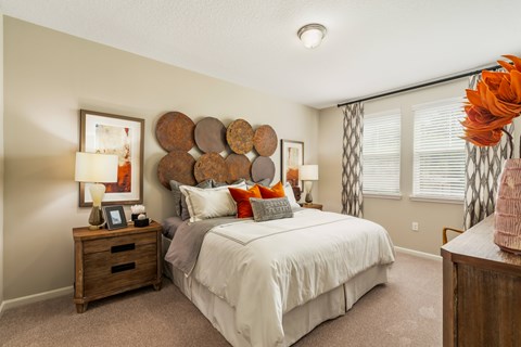 A bedroom with a bed, nightstand, and a wall decoration.