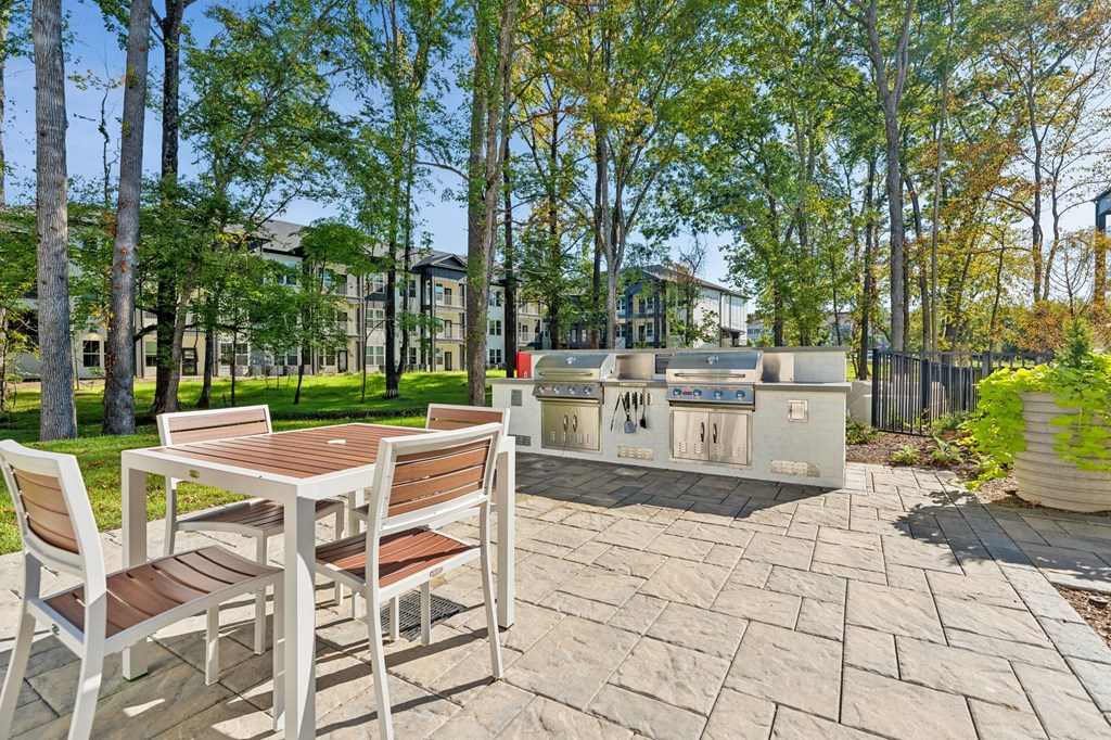 a patio with a table and chairs and a grill