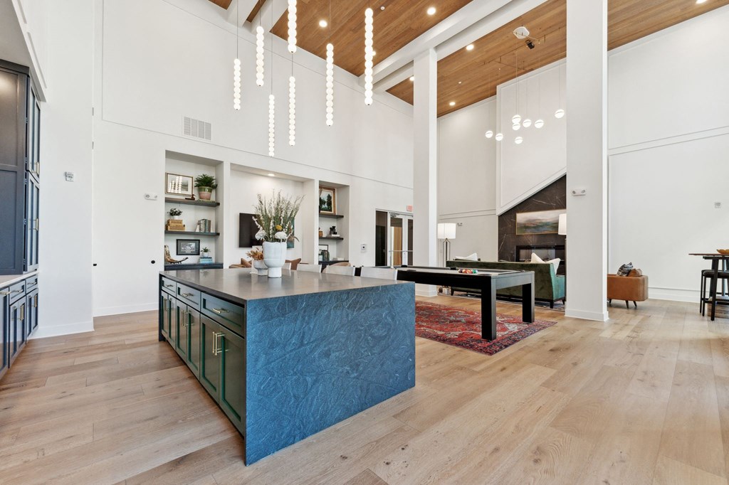 a large kitchen with a blue island and a living room with a pool table