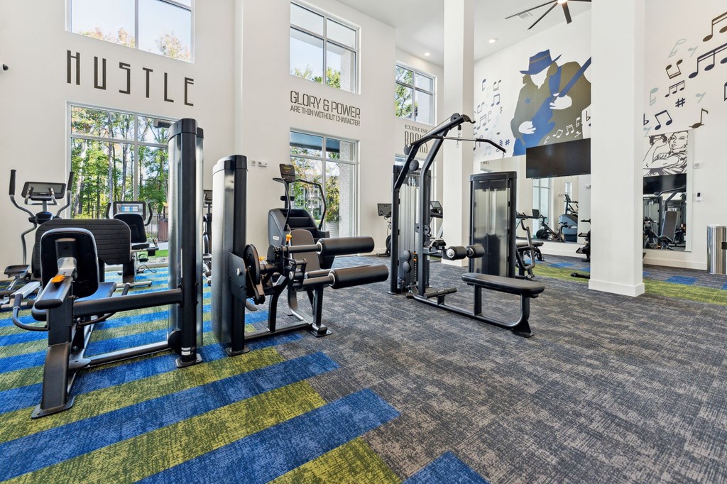 a gym with weights and cardio equipment in a building with large windows