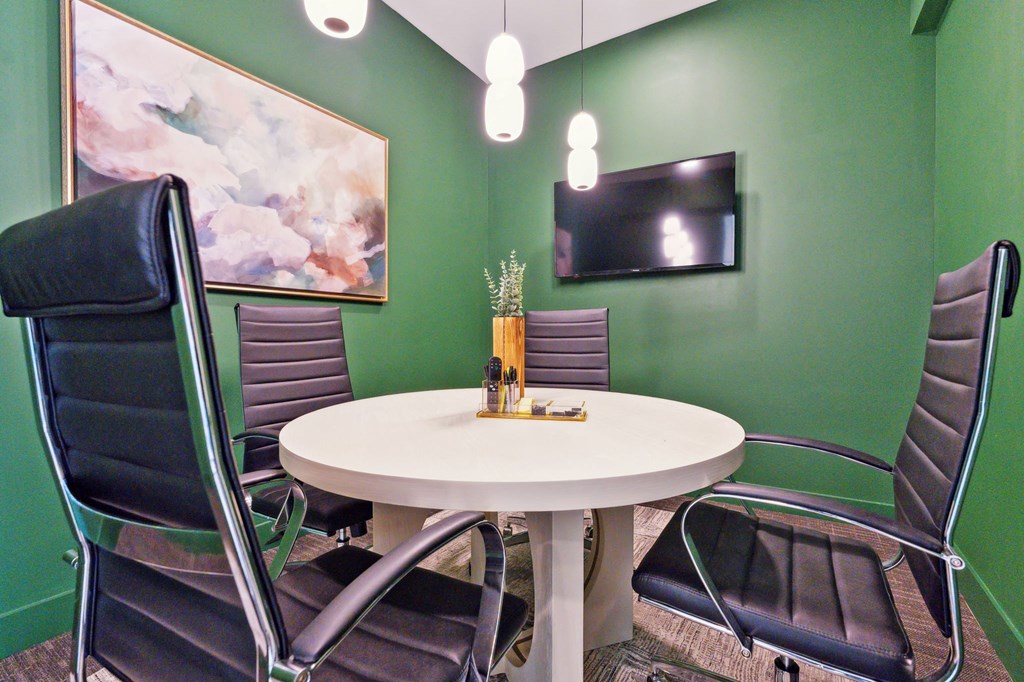 a meeting room with a table and chairs and a television