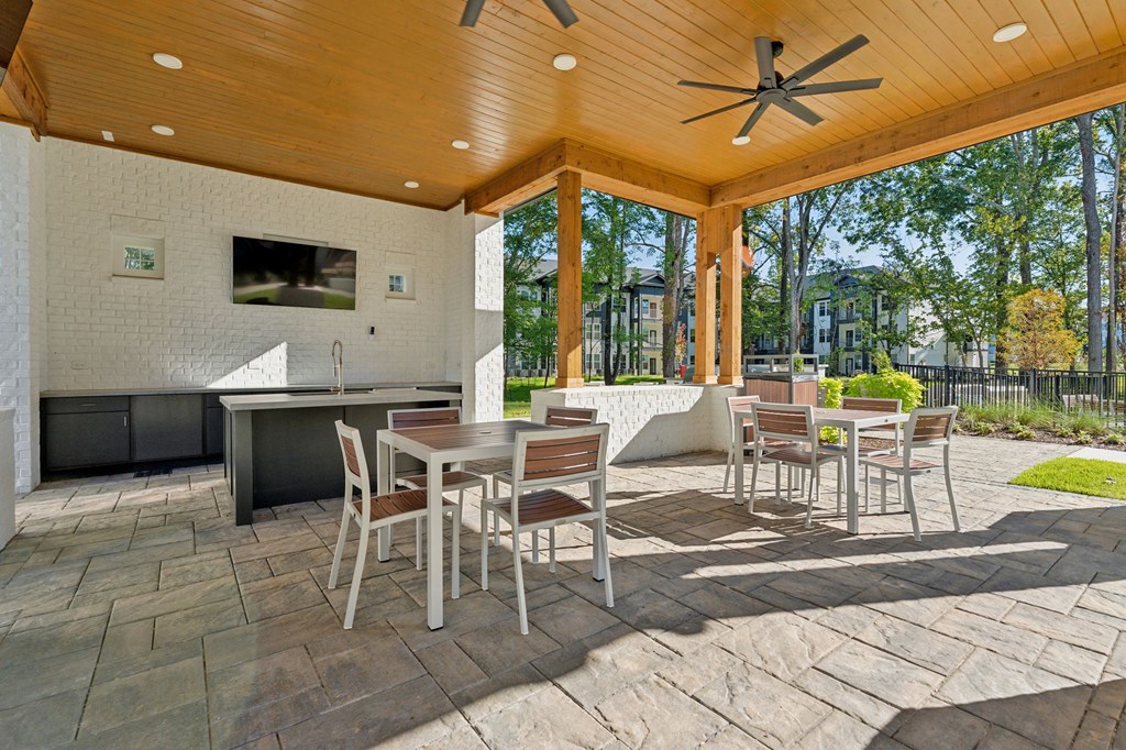 a covered patio with tables and chairs and a tv
