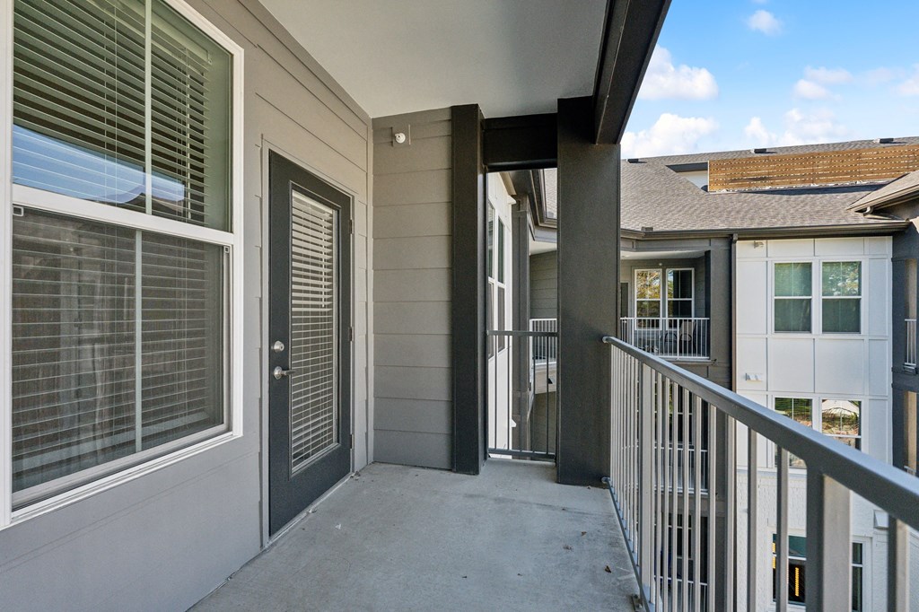 a balcony with a railing and a building with windows and a door