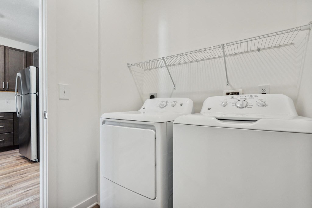 a white washer and dryer in a laundry room with a refrigerator