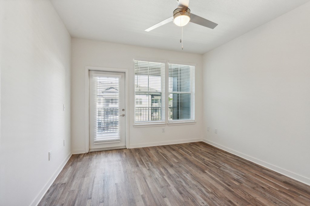 an empty living room with wood floors and a ceiling fan