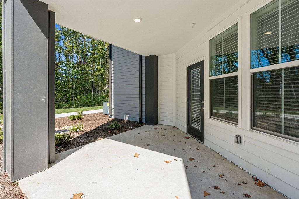the front porch of a house with a concrete walkway and a large window