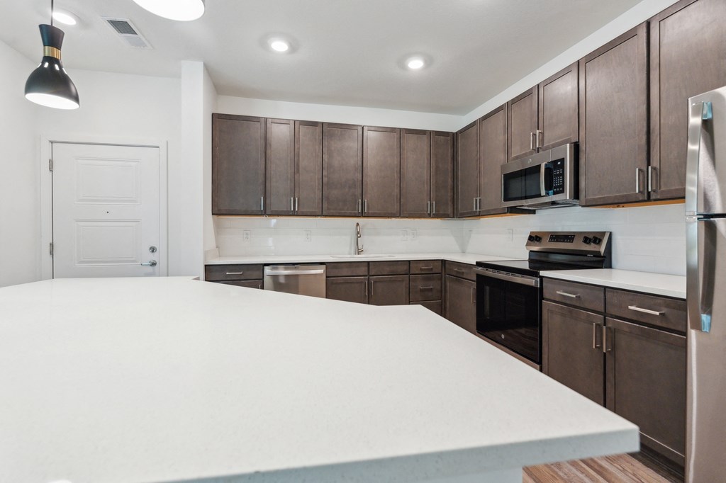 a kitchen with a large white counter top and wooden cabinets