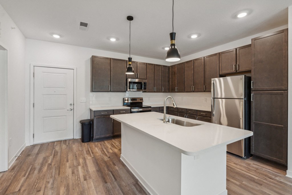 an open kitchen with a large white island and stainless steel appliances