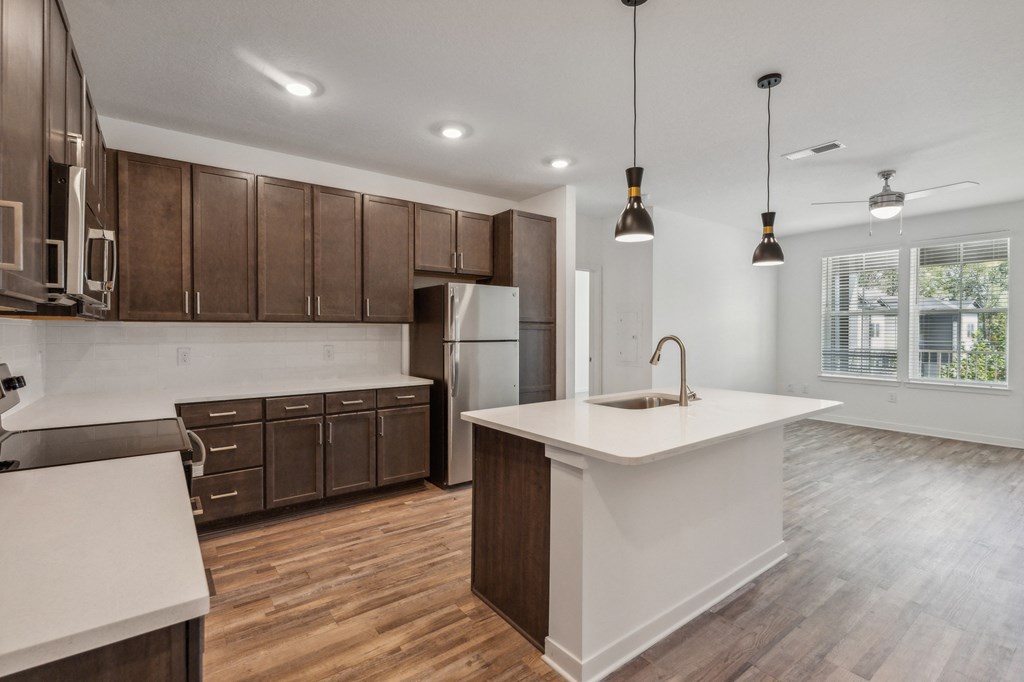an open kitchen with a white counter top and wooden cabinets