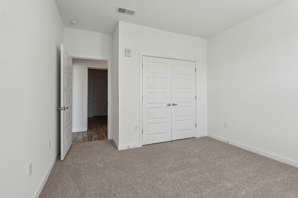 an empty bedroom with a closet and a door to a hallway