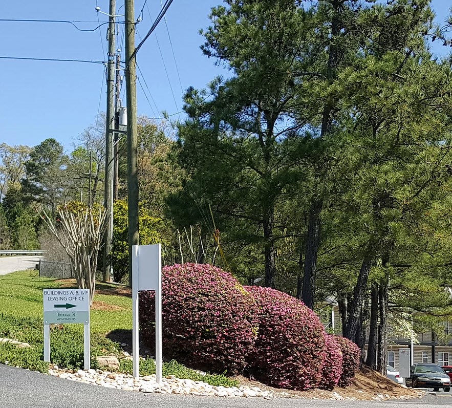 a sign in front of a bush with flowers