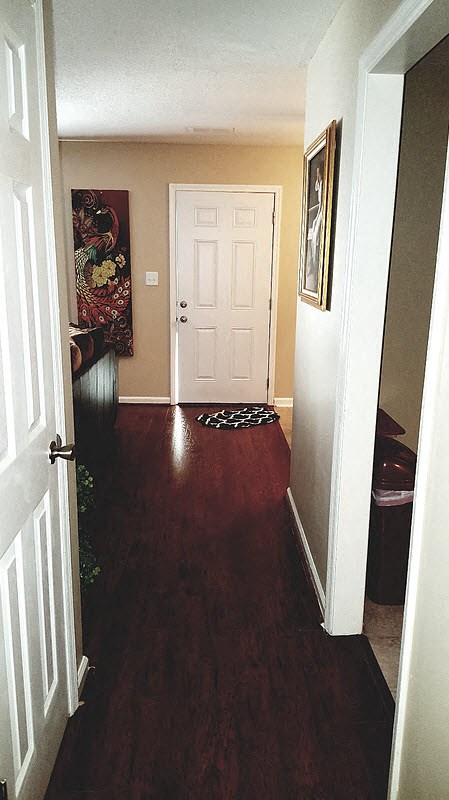 a hallway with a white door and a hard wood floor
