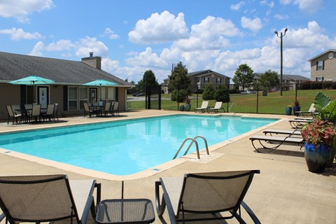 Pool with sundeck, tables, and chairs at The Avery at Auburn Apartments in Auburn, AL
