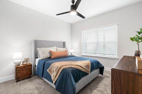 A bedroom with a bed, nightstand, and a ceiling fan.