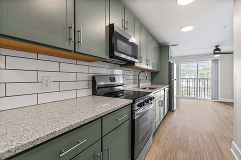 A kitchen with green cabinets and a white tile backsplash.
