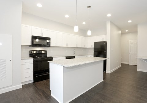 A modern kitchen with a white island and black appliances at Promenade at Founders Square Apartments in Indianapolis, IN