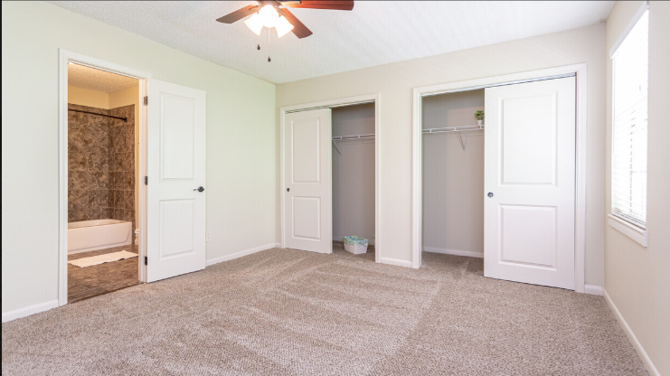 an empty bedroom with three closets and a ceiling fan