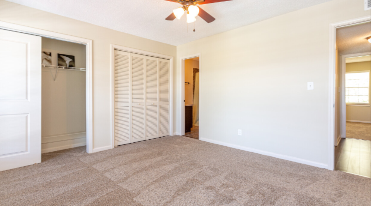 an empty living room with a closet and a ceiling fan