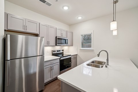 A modern kitchen with a stainless steel refrigerator and white countertops.