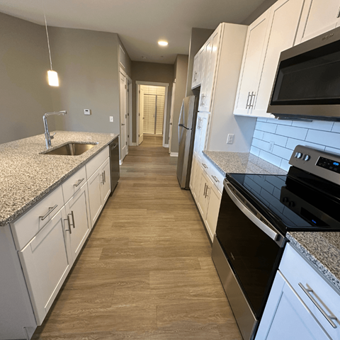 A kitchen with white cabinets and a black stove top oven.