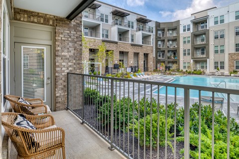 A balcony with chairs and a pool in the background.
