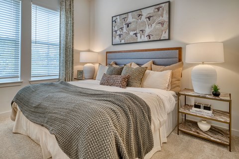 A bedroom with a large bed and a painting above it.