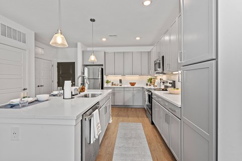 a large white kitchen with stainless steel appliances and white counters