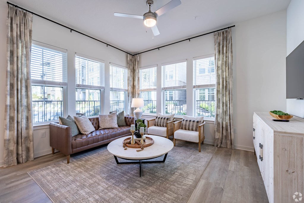 A living room with a brown couch, a white coffee table, and a ceiling fan.