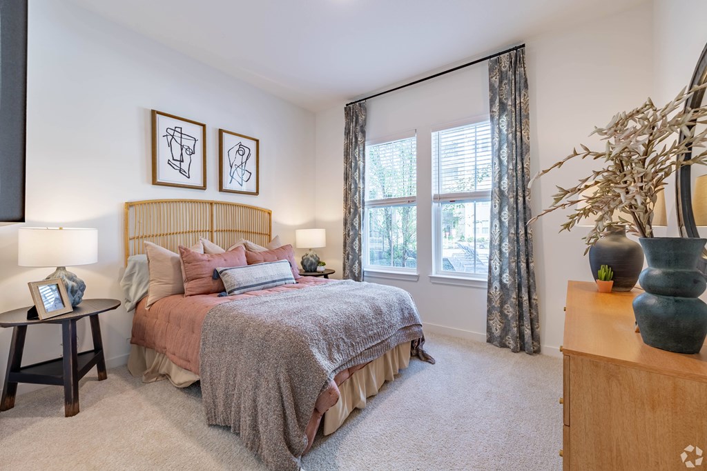A bedroom with a bed, nightstand, and a plant on a dresser.